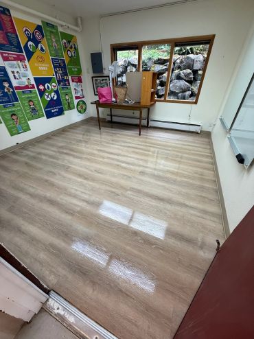 Empty room with wooden floor and colorful posters on wall.