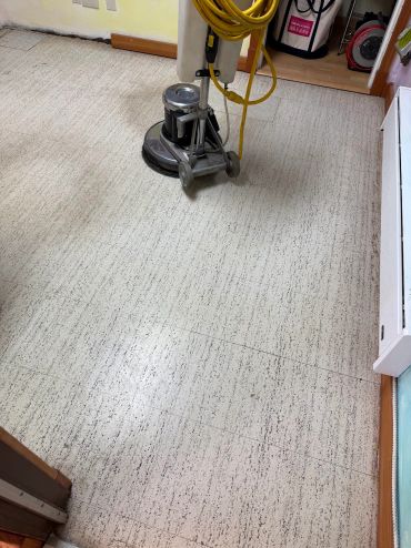 Floor cleaning machine on a speckled linoleum floor.