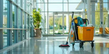 Cleaning cart with mop and supplies in a bright lobby.