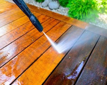 Pressure washing a wooden deck to clean dirt and grime.