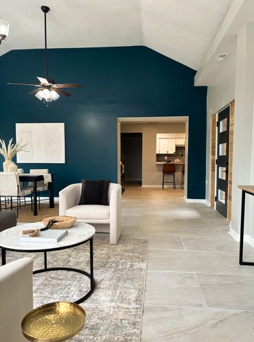 Modern living room with deep teal accent wall and neutral furniture.