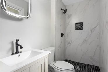 Modern bathroom with black fixtures and marble tiles.