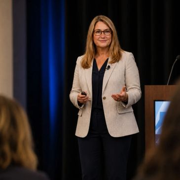 A woman in a blazer giving a presentation on stage.