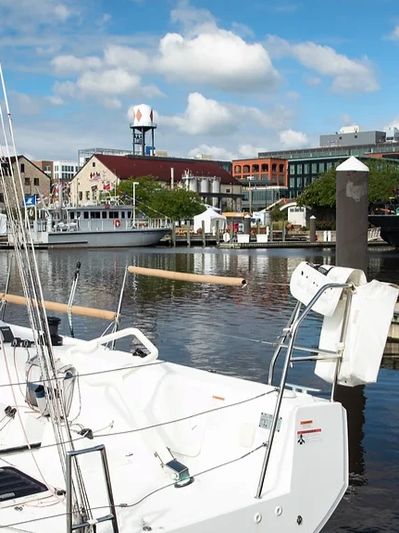Docked white sailboat with buildings in the background.