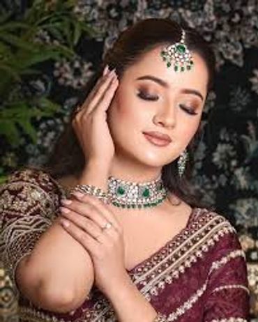 A woman in traditional attire adorned with green gemstone jewelry.