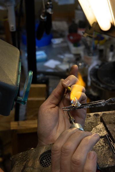 Craftsman using a torch to shape metal in a workshop.