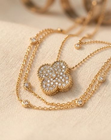 Layered necklace styling in yellow gold featuring pavé diamond clover pendant with milgrain detail a