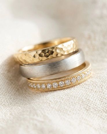 Stacked wedding bands featuring hammered texture yellow gold band, brushed finish white gold band wi