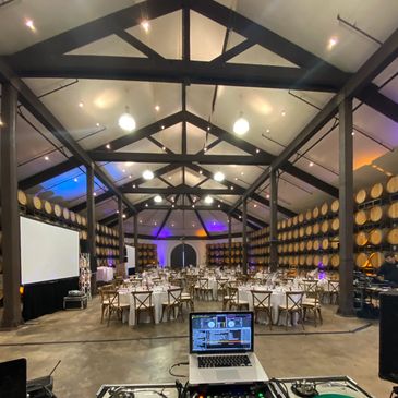 Event setup inside a barrel storage room with tables and DJ equipment.