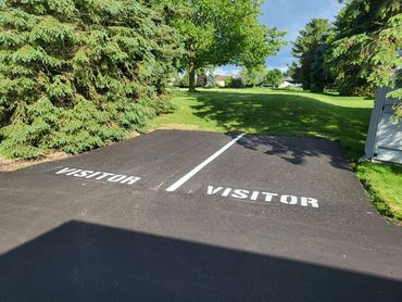 Two adjacent visitor parking spaces marked on a paved area next to greenery.