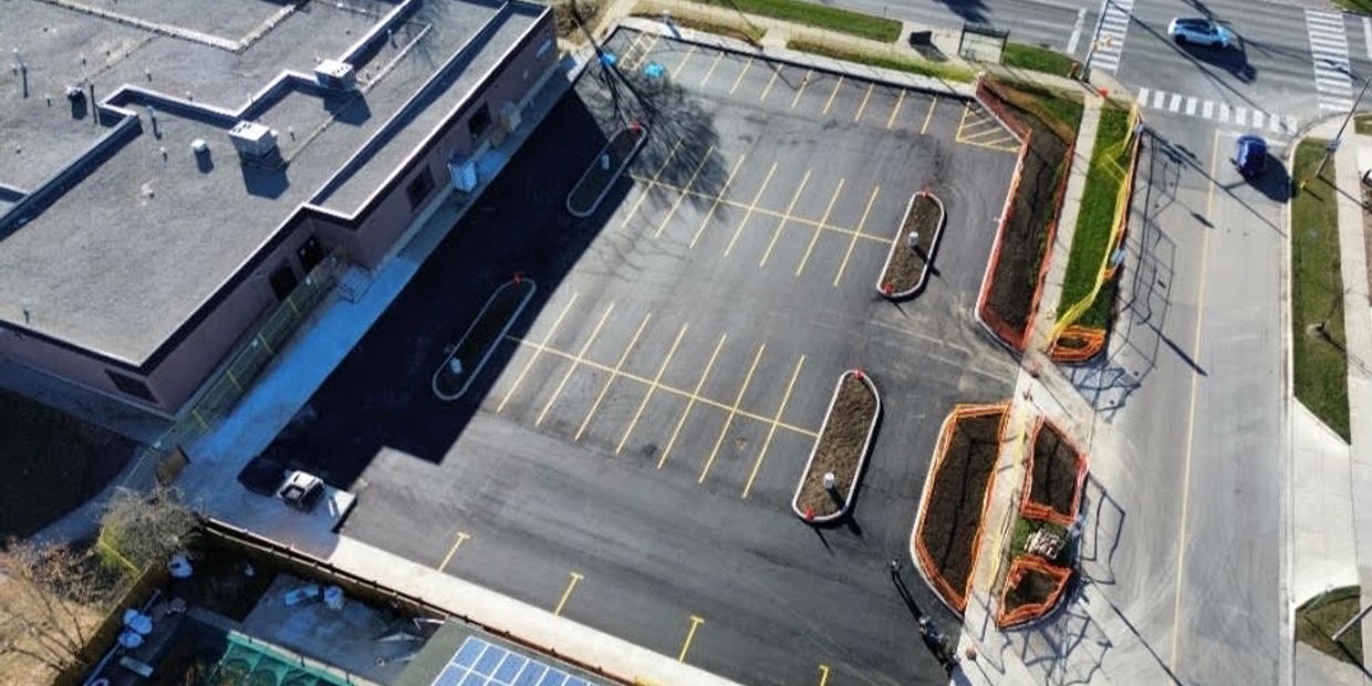 Aerial view of an empty parking lot beside a building with landscaped islands.