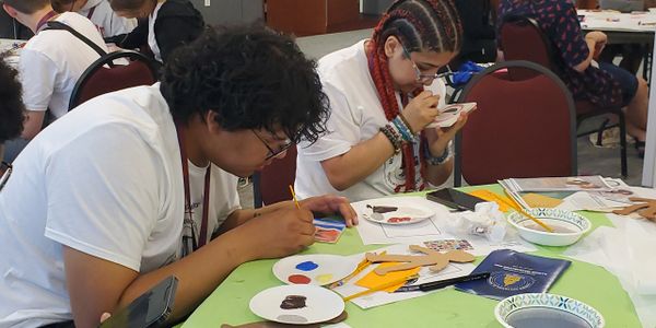 Two individuals focused on painting crafts at a table.