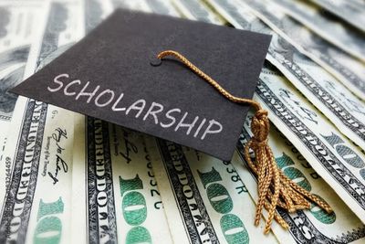 A graduation cap labeled 'Scholarship' on hundred-dollar bills.