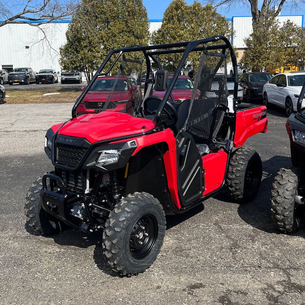 Red Honda Pioneer 520 side-by-side utility vehicle parked outdoors on pavement.