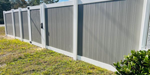 Gray vinyl fence with white framing in a backyard.