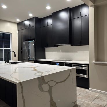 Modern kitchen with black cabinets and white marble countertops.