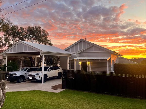 Sunset view over a suburban house with two white cars in the driveway.