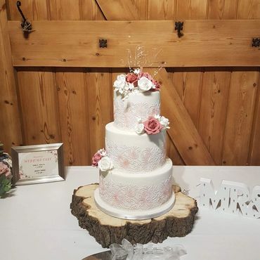 3 tier rustic with bush of pink & white flowers and lace wedding cake