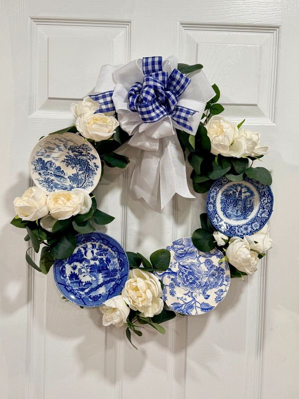 Decorative wreath with blue and white plates and flowers.