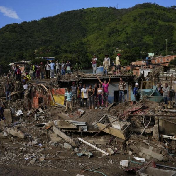 People stand on debris after a disaster in a mountainous area.