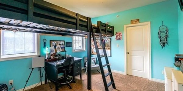 Loft bed with black desk and chair in a bright turquoise bedroom.