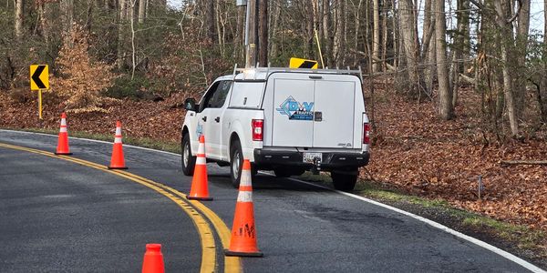 White DMV Traffic truck parked by the roadside with orange cones.