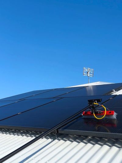 Solar panels installed on a corrugated metal roof under a clear blue sky.