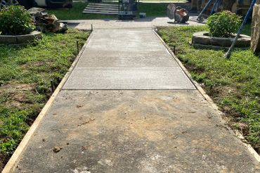 Freshly poured concrete pathway in a garden area.