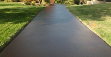 Smooth, freshly paved driveway with green lawns on either side.