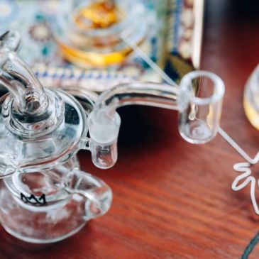A glass dab rig for consuming concentrates on a wooden surface.
