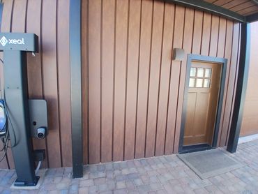 Outdoor wall with a small door and a Xeal charging station.