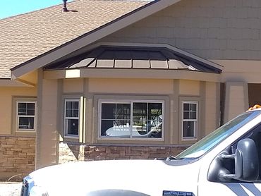 White Ford F-250 truck parked in front of a beige house with large windows.