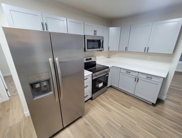 Modern kitchen with stainless steel appliances and light gray cabinets.