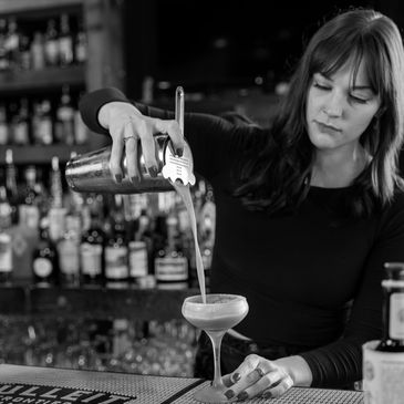 A bartender crafting a cocktail behind the bar at The Reserve.