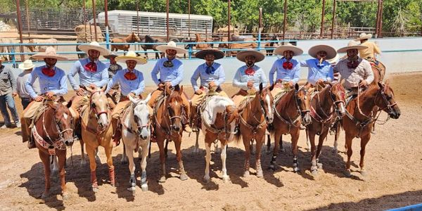 Group of eleven men on horseback wearing traditional attire.