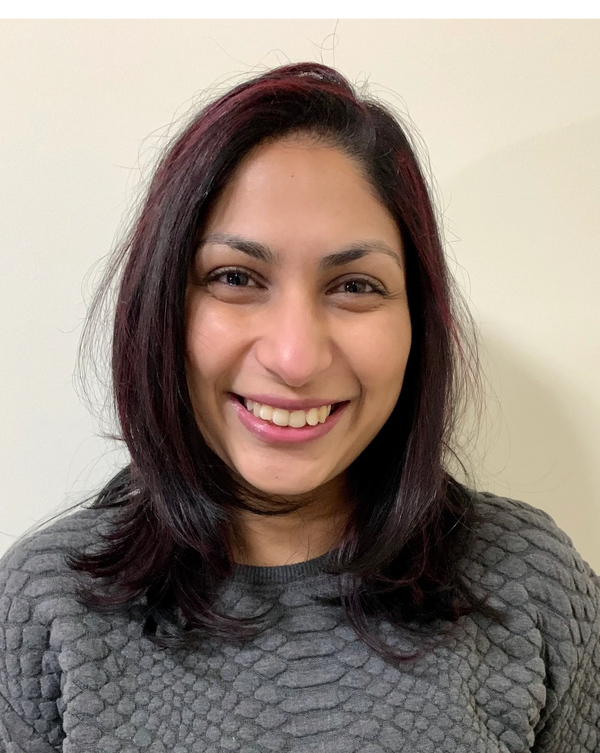 Smiling woman with shoulder-length dark hair and a textured grey sweater.