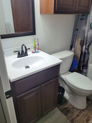 Completed remodel of bathroom, sink, vanity, cabinet, walls, and toilet.