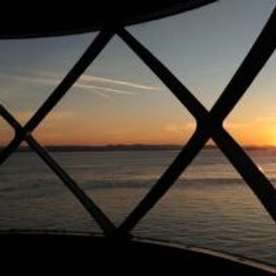 Sunset over water seen through a crisscross window frame.