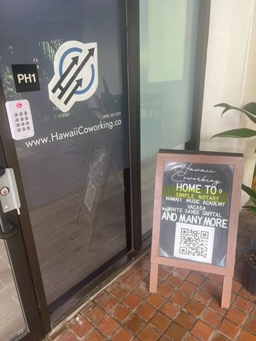 Entrance of Hawaii Coworking with a signboard listing tenants and a QR code.
