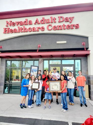 Group of people posing with awards outside Nevada Adult Day Healthcare Centers.