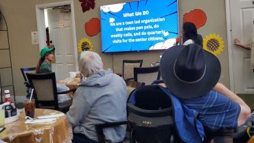 Seniors and volunteers engage in a presentation at a community center.