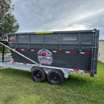 Gray Hutchins Dumpster Rental trailer on grass.