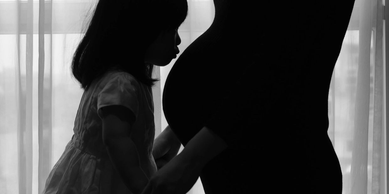 Daughter kissing mother's pregnant belly 