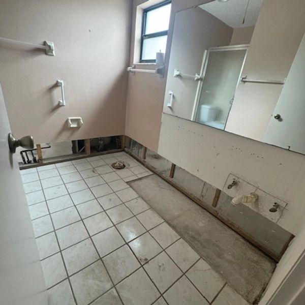 Bathroom under renovation with missing fixtures and exposed wall sections.
