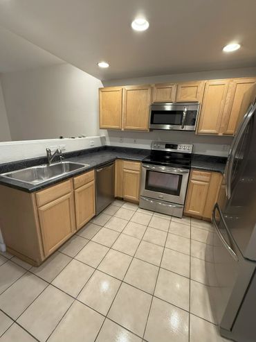 Modern kitchen with stainless steel appliances and light wood cabinets.