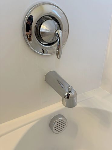 Close-up of a modern chrome bathtub faucet and control handle.