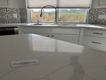 Modern kitchen with marble countertop and patterned backsplash tiles.