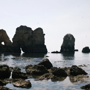 Rock formations rising from calm sea waters under a clear sky.