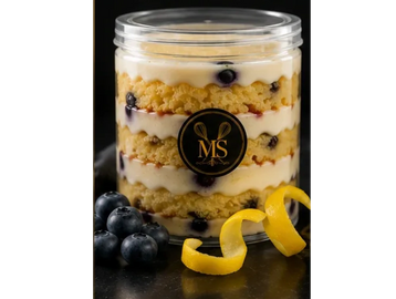 Blueberry lemon cake in a clear jar with lemon peel garnish.