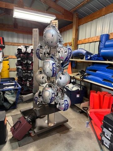 Football helmets organized on a metal rack in a sports storage room.